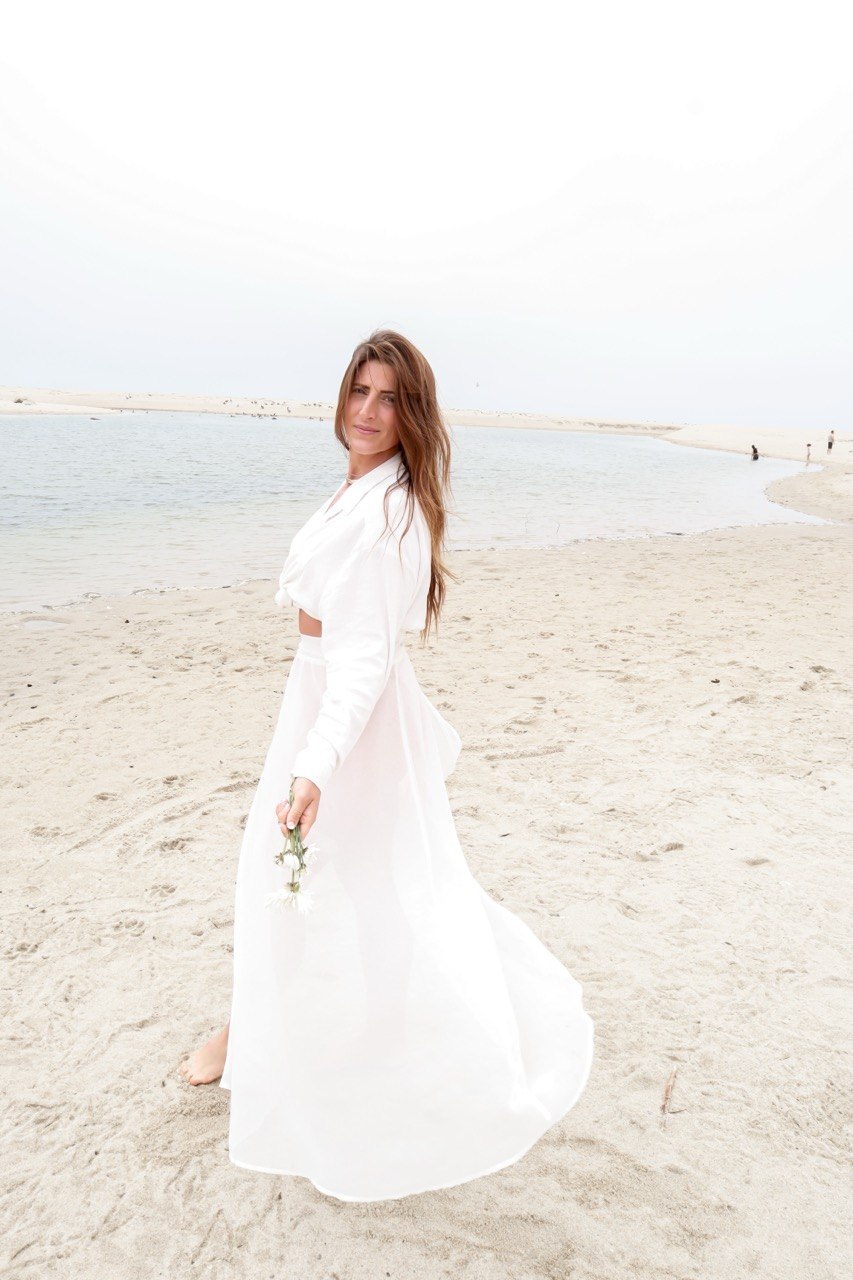 Megan Michele in a white dress beside the water